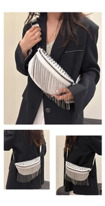 Detail of white half-moon crossbody bag with long silver tassels and punk rivets decor