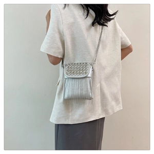 Detail of silver studded crossbody bag with metallic tassels and elegant chain strap