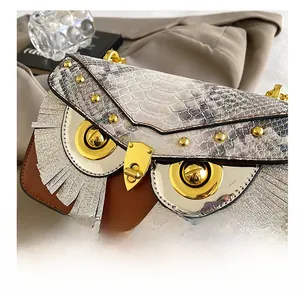 Détail du sac bandoulière hibou avec cuir motif serpent et fermoir pivotant en métal doré