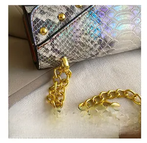 Gros plan d'un sac irisé motif serpent avec clous dorés et bandoulière en chaîne dorée