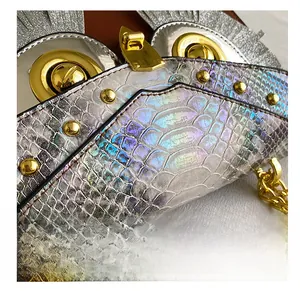 Gros plan sur la texture serpent holographique et boucle hibou dorée du sac à main