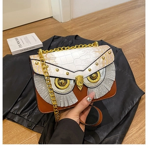 Dettaglio borsa a civetta con pelle a coccodrillo e piume argentate glitterate sulla borsa