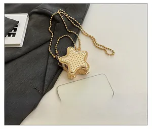 Mini sac étoile dorée avec strass à côté d'un téléphone pour comparer la taille