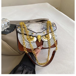 Dettaglio borsa a forma di gufo con trama a serpente e decorazioni occhi metallici