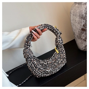 Close-up of leopard print woven crescent bag with decorative side knots and gold zipper