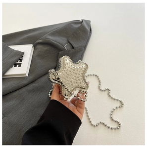 Détail d'un mini sac de soirée argenté en forme d'étoile avec strass et chaîne perlée
