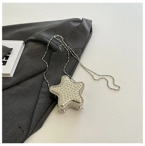 Détail d'une mini pochette argentée en forme d'étoile avec strass et chaîne perlée
