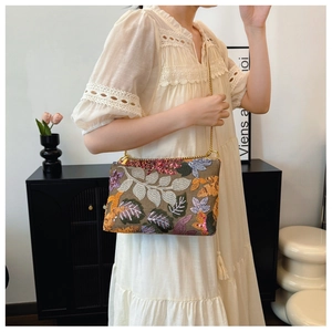 Detail of floral embroidery and sequins on a vintage crossbody bag with gold chain