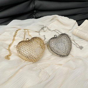 Golden and silver heart-shaped metal mesh clutch bags with chain straps in a top view