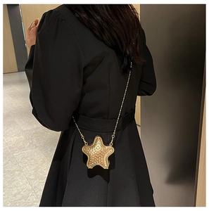 Détail du mini sac étoile doré avec strass et chaîne métallique porté par un mannequin