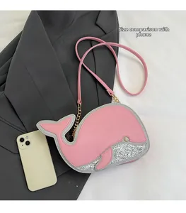 Mini sac dauphin rose avec paillettes argentées et bandoulière à côté d'un téléphone