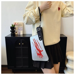 Detail of silver kitchen knife-shaped crossbody bag with red claw marks and black handle
