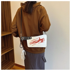 Detail showing creative cleaver-shaped bag with red splatters and skeleton hand charm