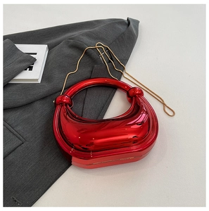 Détail du sac hobo rouge métallisé avec chaîne dorée sur fond de blazer gris