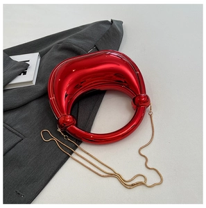 Détail du sac bandoulière rouge en acrylique avec chaîne dorée sur un blazer gris