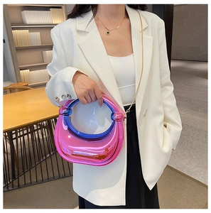 Détail du sac pochette en acrylique dégradé avec chaîne dorée sur un blazer blanc