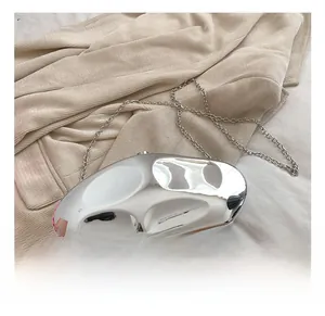 Silver metallic pebble-shaped evening bag with chain strap on beige blazer background