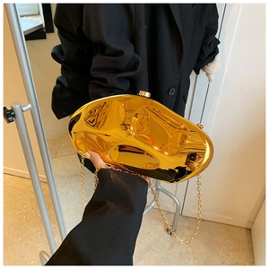 Macro detail of glossy golden irregular stone-shaped clutch bag with metal chain strap