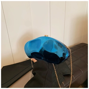 Macro shot of metallic blue pebble clutch bag with gold chain and mirror finish texture