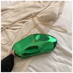 Detailed macro of emerald green pebble clutch bag with polished metallic finish and gold chain