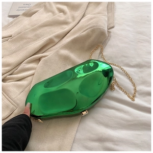 Detail view of a green mirror-finish stone-shaped clutch bag with golden chain strap