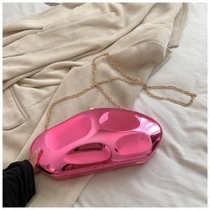 Close-up of bright pink acrylic pebble clutch bag with mirror finish and gold chain strap