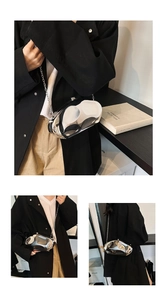 Detailed view of silver mirror acrylic clutch bag with sculptural fluid design and chain