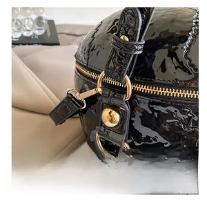 Detail of the high-shine crocodile pattern leather and gold metal hooks on the skull bag