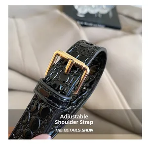 Detail of adjustable black croc-embossed leather strap with polished gold buckle closure