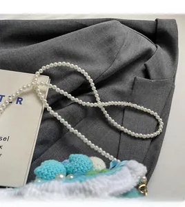 Détail du sac tricoté en forme de gâteau avec bandoulière en perles et nœud soyeux