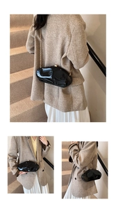 Detail of black acrylic stone-shaped handbag with golden chain strap on a brown blazer