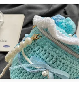 Détail du sac tricoté bleu avec poignée en perles, nœud en soie et ferrures dorées