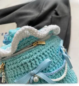 Détail de la fermeture éclair en métal doré sur un sac tricoté bleu fait main