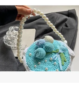 Détail du sac tricoté en forme de gâteau bleu avec poignée en perles et fleurs