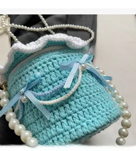 Gros plan d'un sac gâteau en crochet bleu ciel avec volants blancs et perles