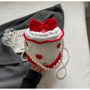 Détail du sac tricoté en forme de gâteau avec nœud rouge et bandoulière perles