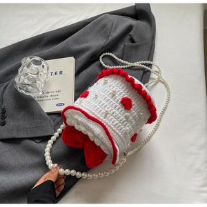 Détail d'un sac gâteau tricoté main avec bandoulière perle et broderie cœur rouge