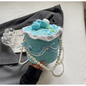 Détail macro du sac gâteau tricoté main avec perles et décorations de baies bleues