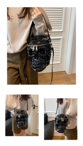 Detail view of glossy skull-shaped crossbody bag with gold zippers and metal hardware
