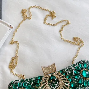 Detailed close-up of dark green rhinestone evening bag with elegant golden chain strap