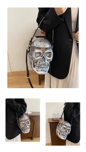 Macro shot of silver skull crossbody bag with textured bone details and gold zippers