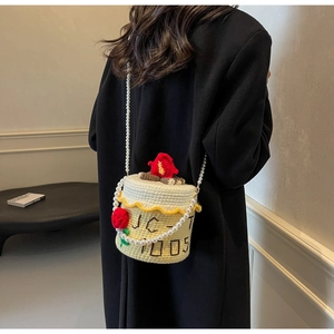 Détail d'un sac tricoté créatif en forme de gâteau avec chaîne en perles et fleurs en 3D