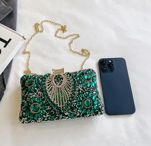 Macro shot of green rhinestone evening bag showing size comparison with a smartphone