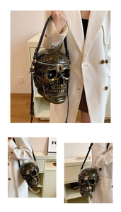 Close-up of metallic bronze skull shoulder bag with dual zippers and leather strap