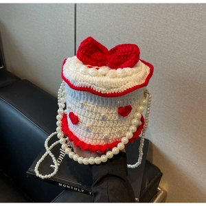 Détail du sac gâteau au crochet avec nœud rouge, perles et texture tricotée