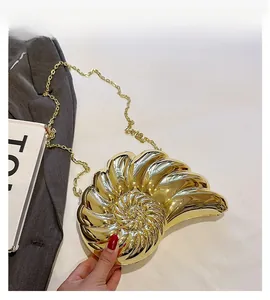 Détail d'un sac de soirée doré en forme de coquillage avec une bandoulière chaîne