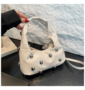 Détail du sac sous l'aisselle en cuir blanc crème avec rivets sphériques argentés