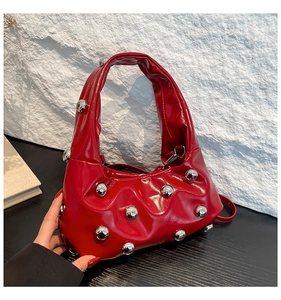 Gros plan d'un sac à main rouge verni avec rivets argentés et design avant-gardiste unique