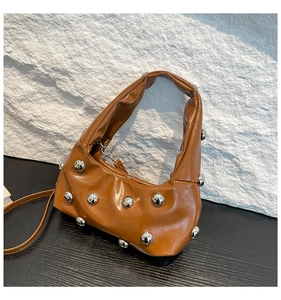 Détail du sac hobo caramel avec texture cuir brillant et clous argentés élégants
