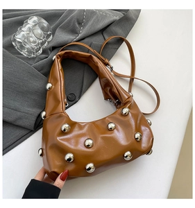Détail du sac croissant marron caramel avec rivets argentés sur cuir froissé brillant